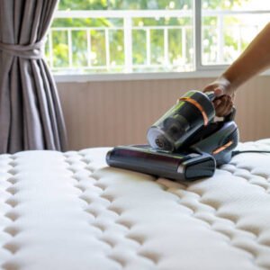 Cropped view of man removing dust on mattress with vacuum cleaner